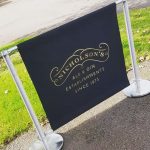 Nicholson's Canvas Café Banner in Black with Metallic Gold Vinyl between Advance Café Barrier Post