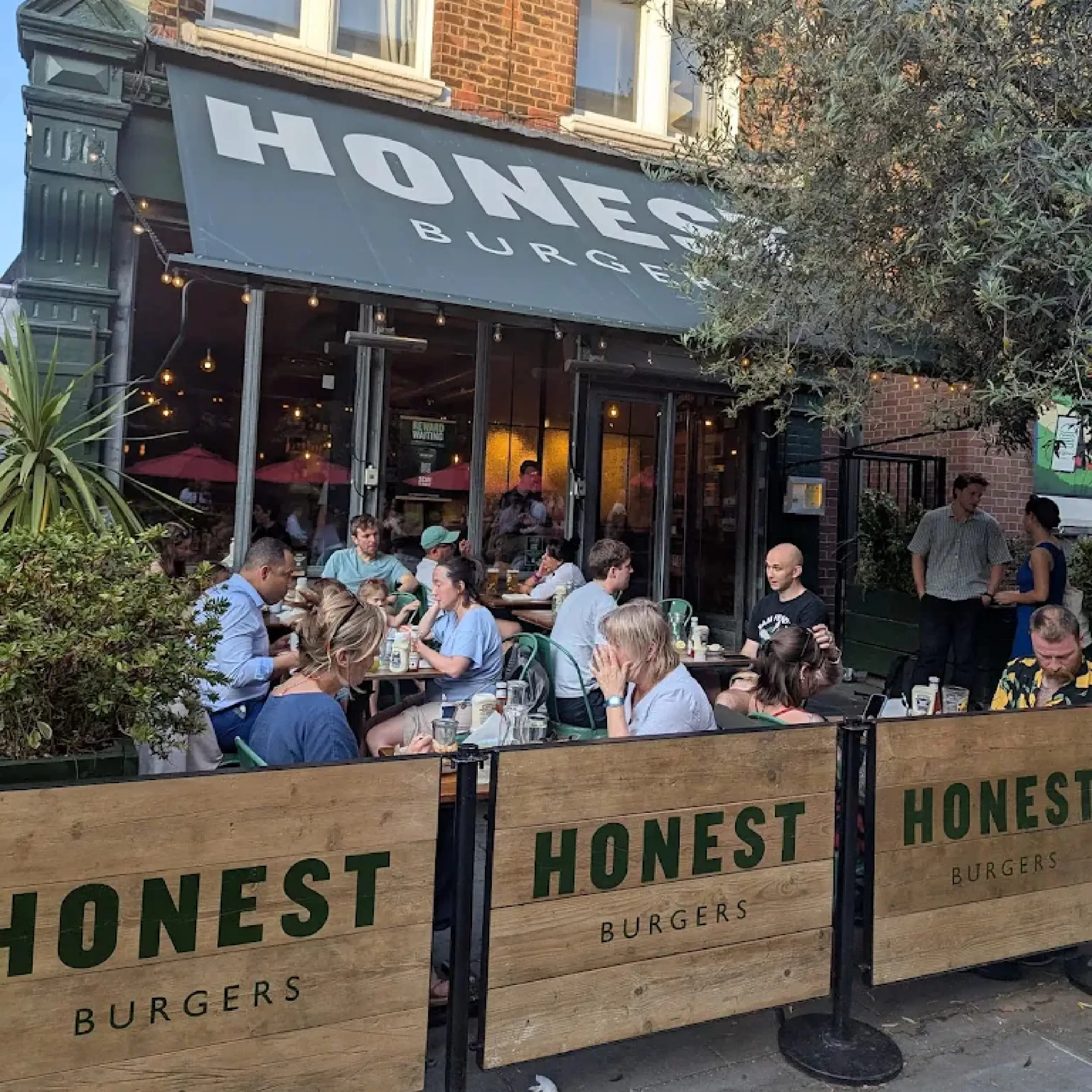 Honest Burger 1 - Wooden Framed Cafe Panels Wooden Framed Cafe Panels outside Honest Burger, Wooden Restaurant Panels, Cafe Screens, Powder Coated Cafe Barrier Posts, Bespoke Cafe Panels, Custom-Made Cafe Panels, Commercial Cafe Panels, Hospitality Cafe Panels, printed cafe barriers